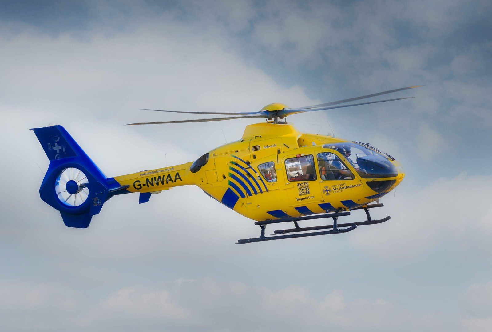 why-choose-us Emergency air ambulance helicopter flying over Blackpool, UK, under a clear sky.